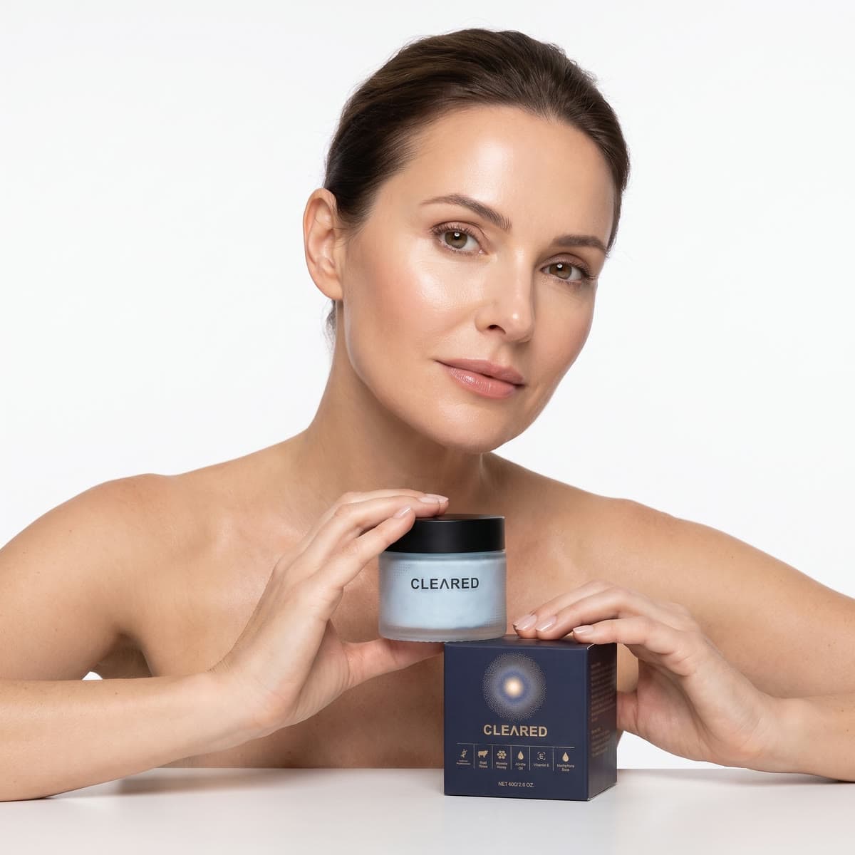 A model resting her hands on the CLEARED jar and box