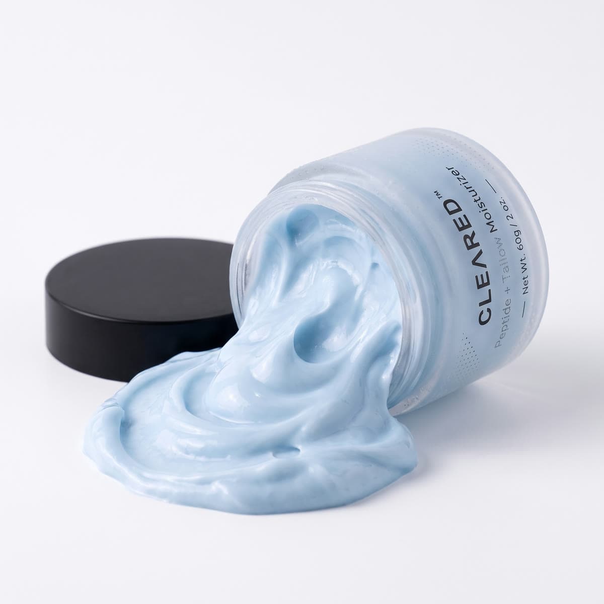 An open jar of CLEARED with the whipped blue cream spilling out